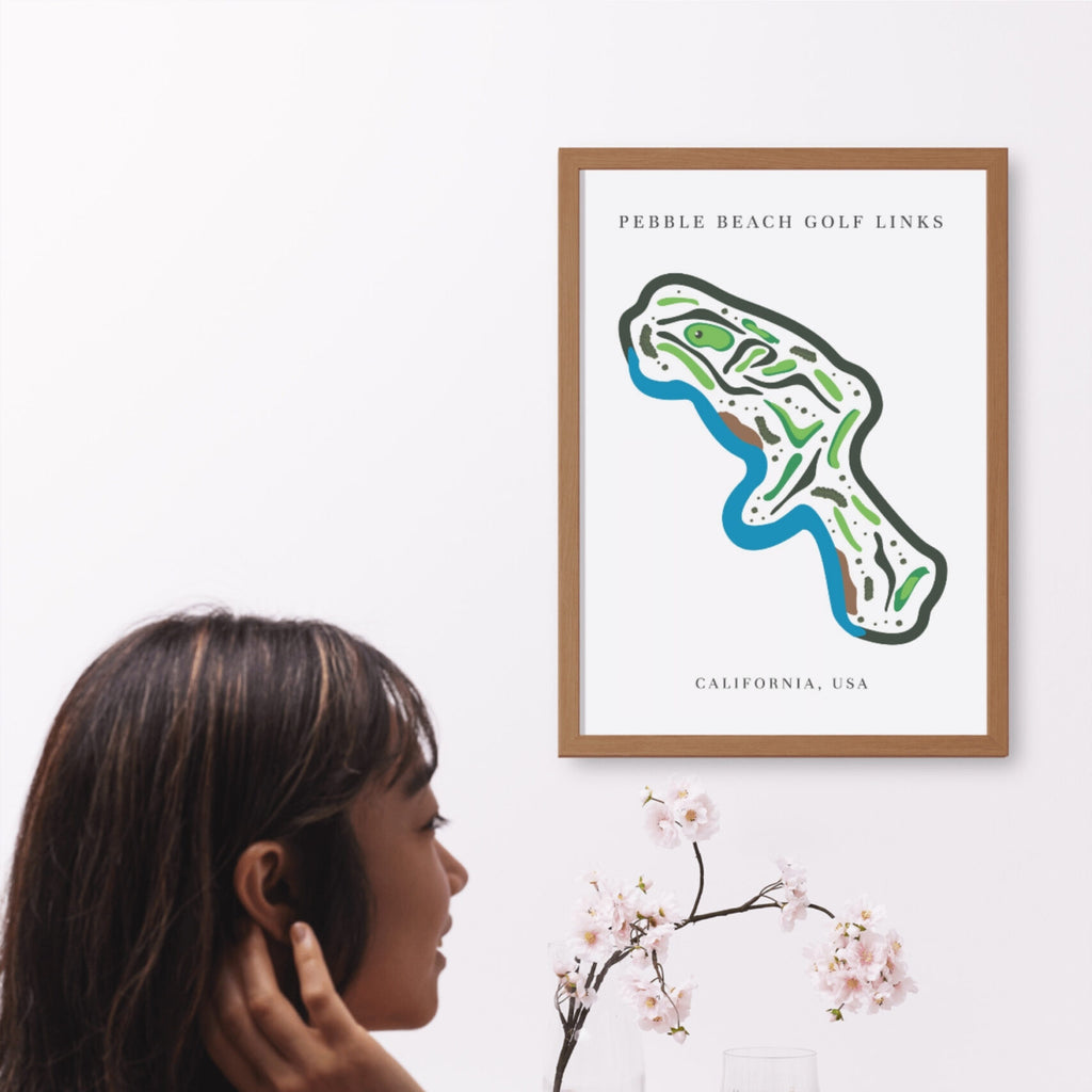 Framed map of Pebble Beach Golf Links on a wall with a woman looking at it.