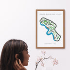 Framed map of Pebble Beach Golf Links on a wall with a woman looking at it.